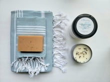 Load image into Gallery viewer, Light Blue set of Turkish bath and hand towels with tassels, a bar of soap, a eucalyptus mint bath salts, and a lavender sage candle on a white background.