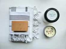 Load image into Gallery viewer, White set of Turkish bath and hand towels with tassels, a bar of soap, a eucalyptus mint bath salts, and a lavender sage candle on a white background.