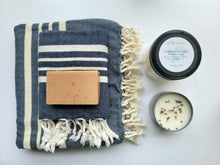 Load image into Gallery viewer, Navy set of Turkish bath and hand towels with tassels, a bar of soap, a eucalyptus mint bath salts, and a lavender sage candle on a white background.
